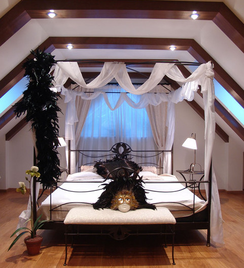 Фотография интерьера спальни в мансарде с железной двуспальной кроватью