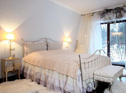 Фотография интерьера спальни с высокой металлической кроватью и большим окном