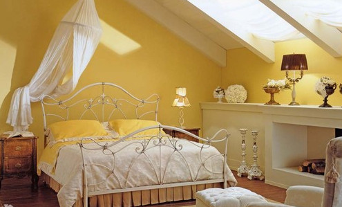 Фотография золотой спальни в мансарде с железной ажурной кроватью