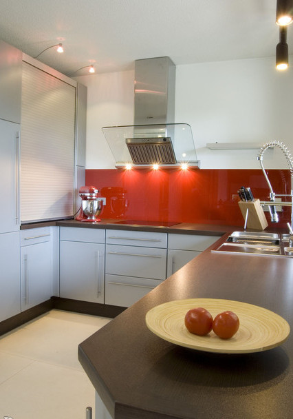 Фотография интерьера голубой угловой кухни с темной столешницей и красной стеновой панелью